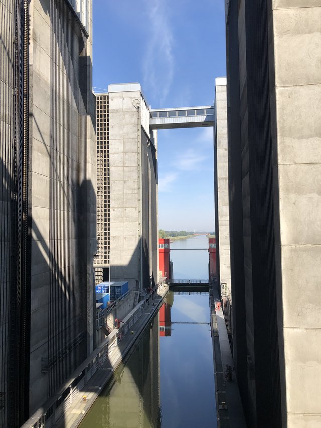 Blick in die Kammer des Schiffshebewerks Scharnebeck bei Lüneburg mit massiven Betontürmen, rotem Hubtor und spiegelnder Wasserfläche
