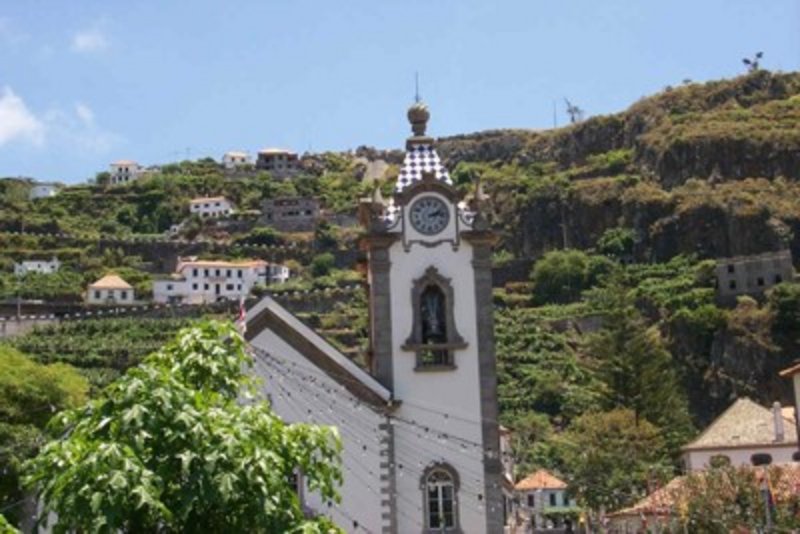 Die Pfarrkirche Igreja de Nossa Senhora da Luz in Ponta do Sol – weiß verputzte Dorfkirche mit Uhrturm, umgeben von steilen Bananenfeldern.