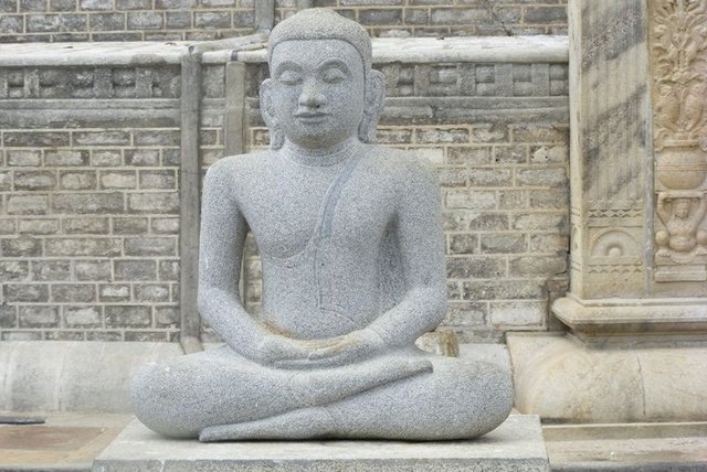 Buddha-Statue in Meditationshaltung vor Tempelmauer in Anuradhapura, einer der ältesten Städte Sri Lankas
